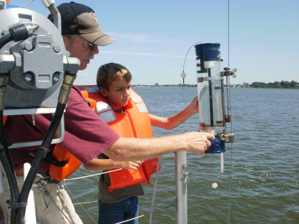 AWRI vessel staff and an elementary student collect water from the W.G. Jackson using a Van Dorn bottle sampler.